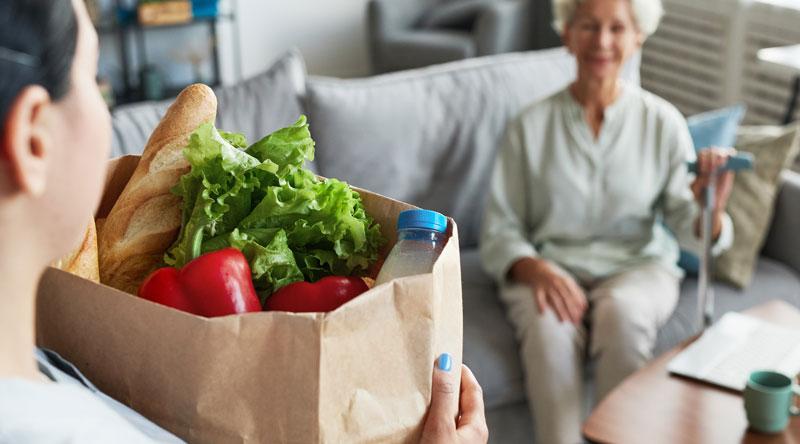 Carer helping elderly woman with shopping
