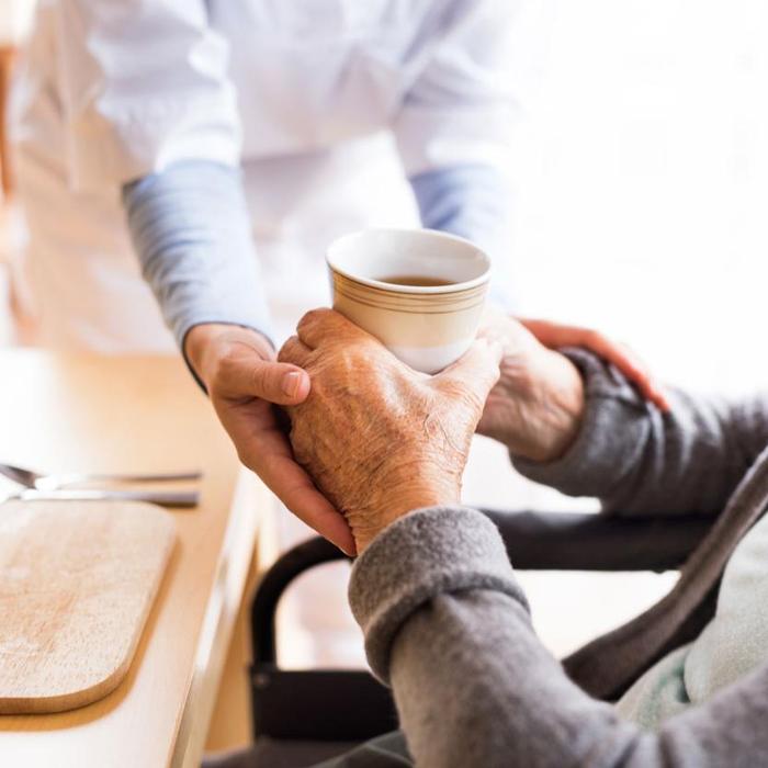 carer giving elderly person a coffee